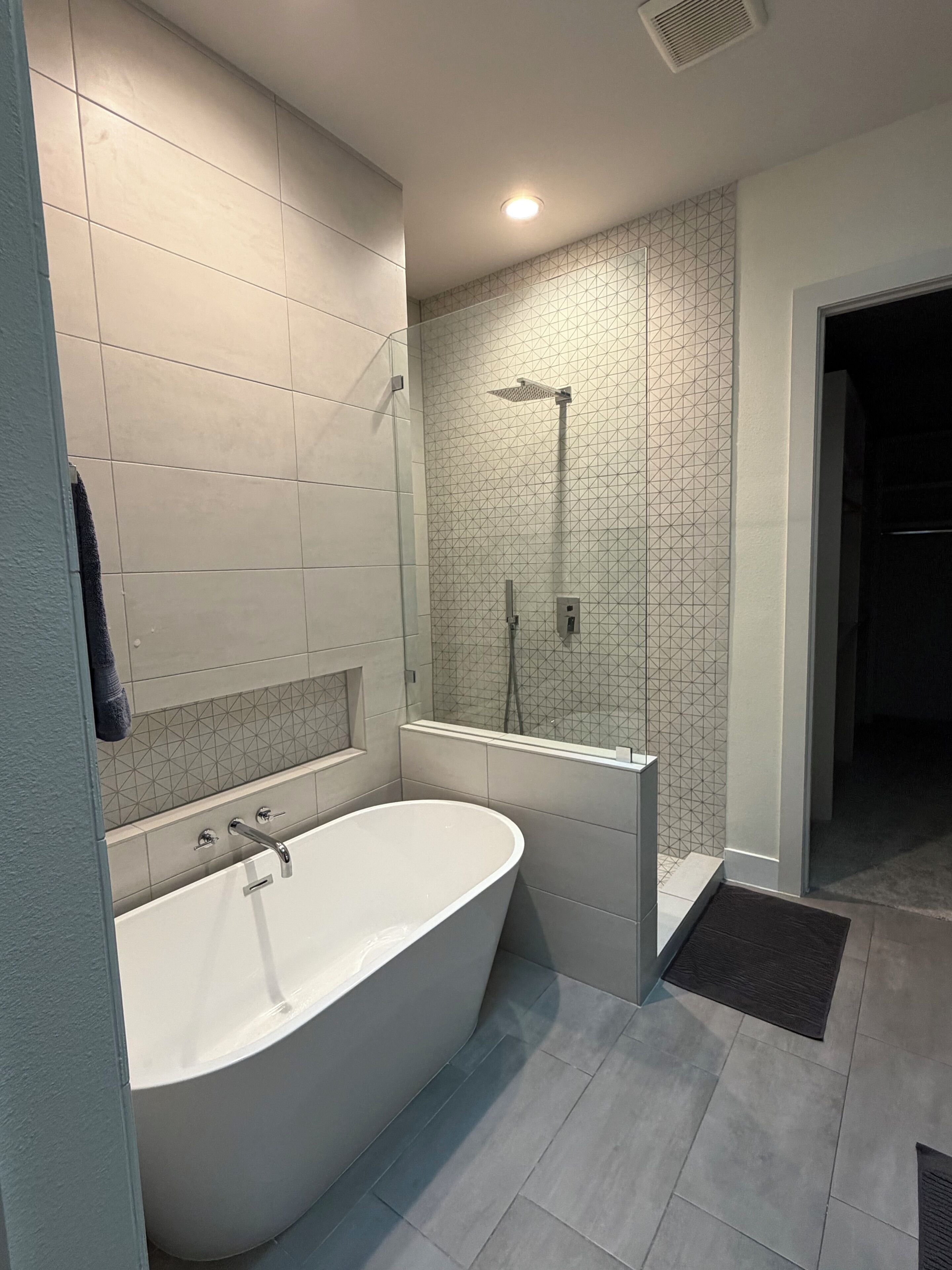 Ein modernes Badezimmer mit freistehender Badewanne, Dusche und großem Spiegel.