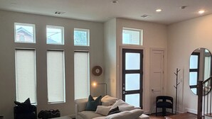A modern living room with a sofa, a dining table, and a staircase leading to another level. - 3Bed Sports Fan Oasis. 5 mins Astros, 10 mins NRG. (Houston)