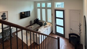 A spacious living area with a staircase, a flat-screen TV, a sofa, and a dining area. - 3Bed Sports Fan Oasis. 5 mins Astros, 10 mins NRG. (Houston)