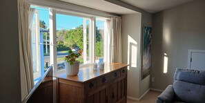 A room with a wooden cabinet, a potted plant, a gray armchair, and a painting on the wall. - Studio apartment in Central Auckland district close to transport (Auckland)