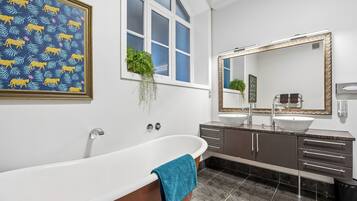 Un bagno moderno con una vasca freestanding, due lavabi, uno specchio grande e una finestra con vista.