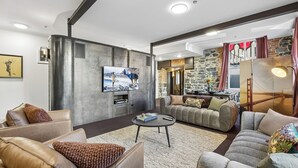 A modern living room with a flat-screen TV, leather sofas, a coffee table, and a stone wall.