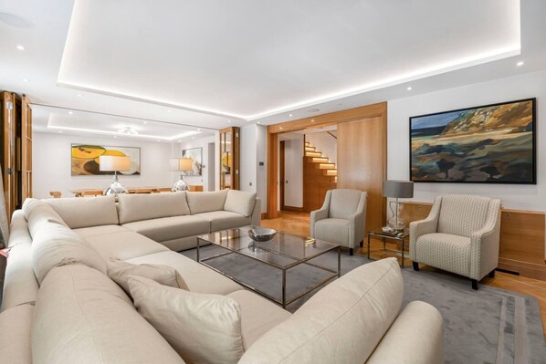 A modern living room with a sofa set, a coffee table, and a painting on the wall. - Mayfair 3-bed With Central AC Upper Grosvenor St (London)