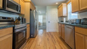 Una cucina con mobili in legno, elettrodomestici in acciaio inossidabile e pavimento in legno.