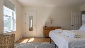 Camera da letto con un letto, una cassettiera, uno specchio e una finestra con persiane.