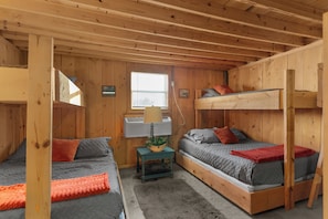 A wooden cabin with bunk beds, a small table with a lamp, and a window. - Spacious Brimstone Cabin-Sleeps 10-Hot Tubs-Fire Pits- Gated-Plenty of Parking (Huntsville)