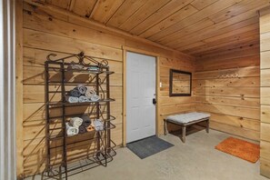 A wooden interior with a metal rack holding towels, a white door, a bench, and a small rug. - Spacious Brimstone Cabin-Sleeps 10-Hot Tubs-Fire Pits- Gated-Plenty of Parking (Huntsville)