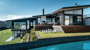 A modern house with a pool, a deck, and a view of the landscape. - Tradewinds Retreat by Waiheke Pure - Views views views, pool, spa, luxurious spacious living (Waiheke Island)
