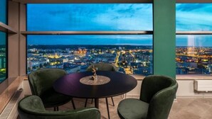 Une pièce dotée d’une grande fenêtre donnant sur une vue panoramique de la ville la nuit.