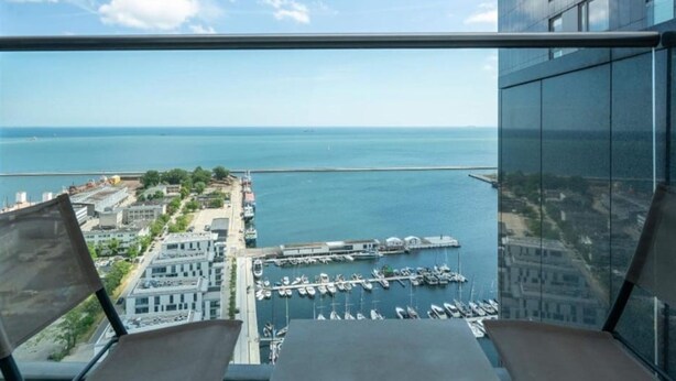 Un immeuble de grande hauteur offrant une vue sur un port de plaisance et la mer.