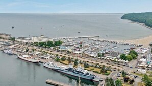 Une marina située sur la côte, avec des bateaux amarrés, un grand navire et une zone de plage.