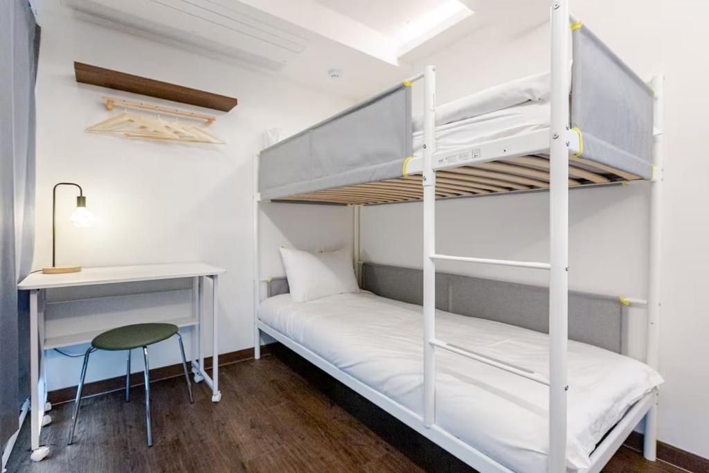 Een stapelbed met een bureau en stoel, een kledingrek en een dakraam.