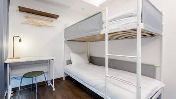 Een stapelbed met een bureau en stoel, een kledingrek en een dakraam.
