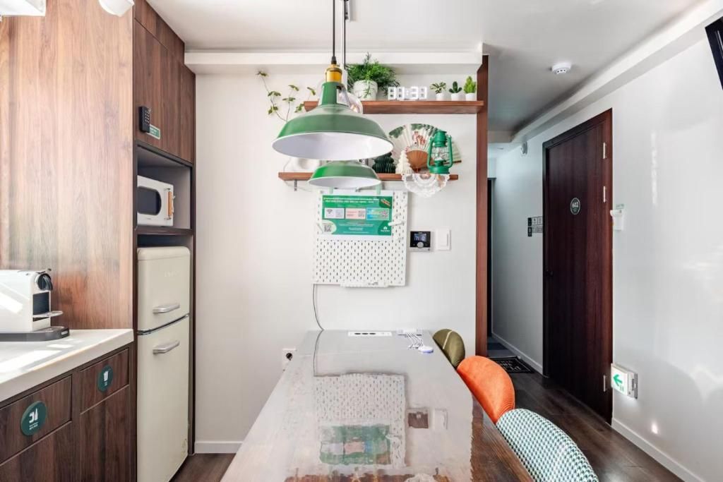 A compact kitchen with a microwave, a coffee machine, and a hanging green pendant light.