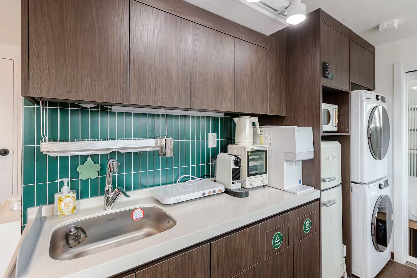 Una cucina accessoriata con lavello, macchina del caffè, forno a microonde e lavatrice e asciugatrice affiancate.