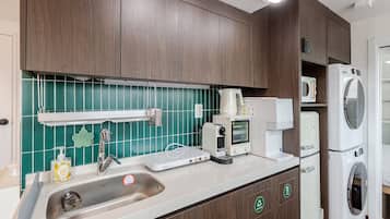Una cucina accessoriata con lavello, macchina del caffè, forno a microonde e lavatrice e asciugatrice affiancate.