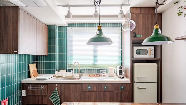 Cozinha com bancada de madeira, pia, micro-ondas e luminárias pendentes.