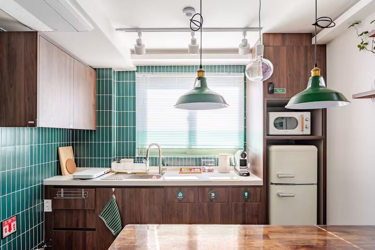 Una cocina con encimera de madera, un fregadero, un microondas y lámparas colgantes.