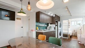 Une cuisine moderne avec des meubles de rangement en bois foncé, un réfrigérateur en acier inoxydable et un four à micro-ondes encastré.