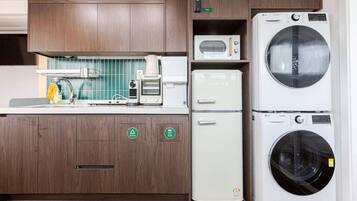 Een kleine keuken met een magnetron, een koffiezetapparaat en een wasmachine.