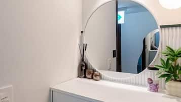 A bathroom with a white vanity, a round mirror, and a potted plant.