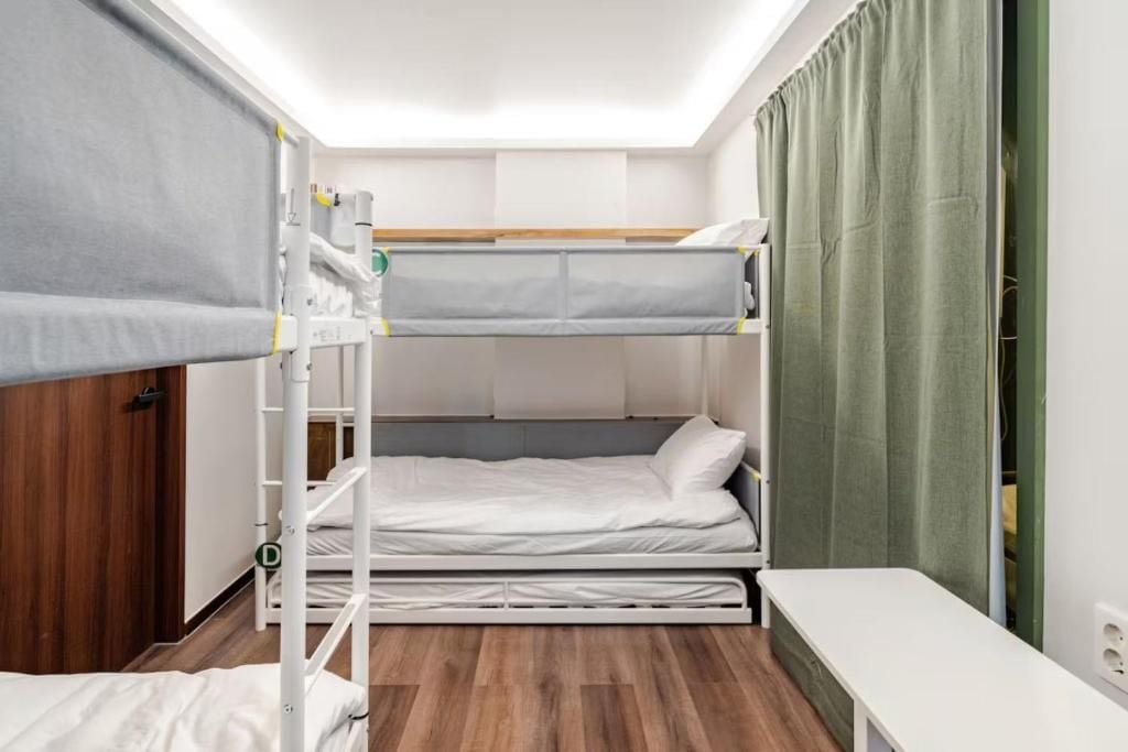 A bunk bed room with a desk and a green curtain.