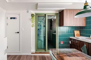 Una cucina con piano di lavoro in legno, una lampada a sospensione verde e una porta con vetri decorati.