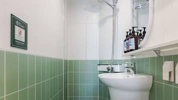 A bathroom with a white sink, a mirror, and a shower.