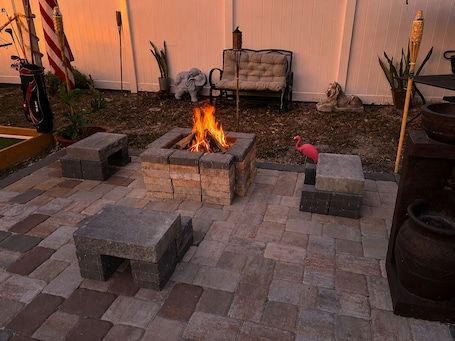 A fire pit surrounded by stone seating, a lounge chair, and a flamingo statue.. Minutes Away from the Famous Universal Studios & Other Renowned Attractions