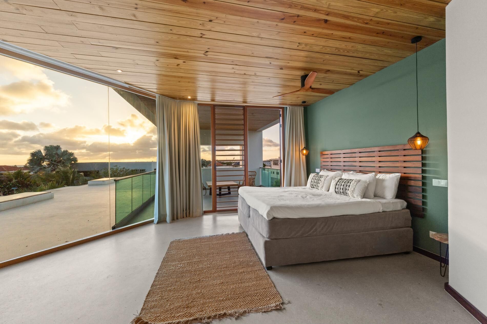 Une chambre avec un grand lit, une vue sur le ciel et un balcon.