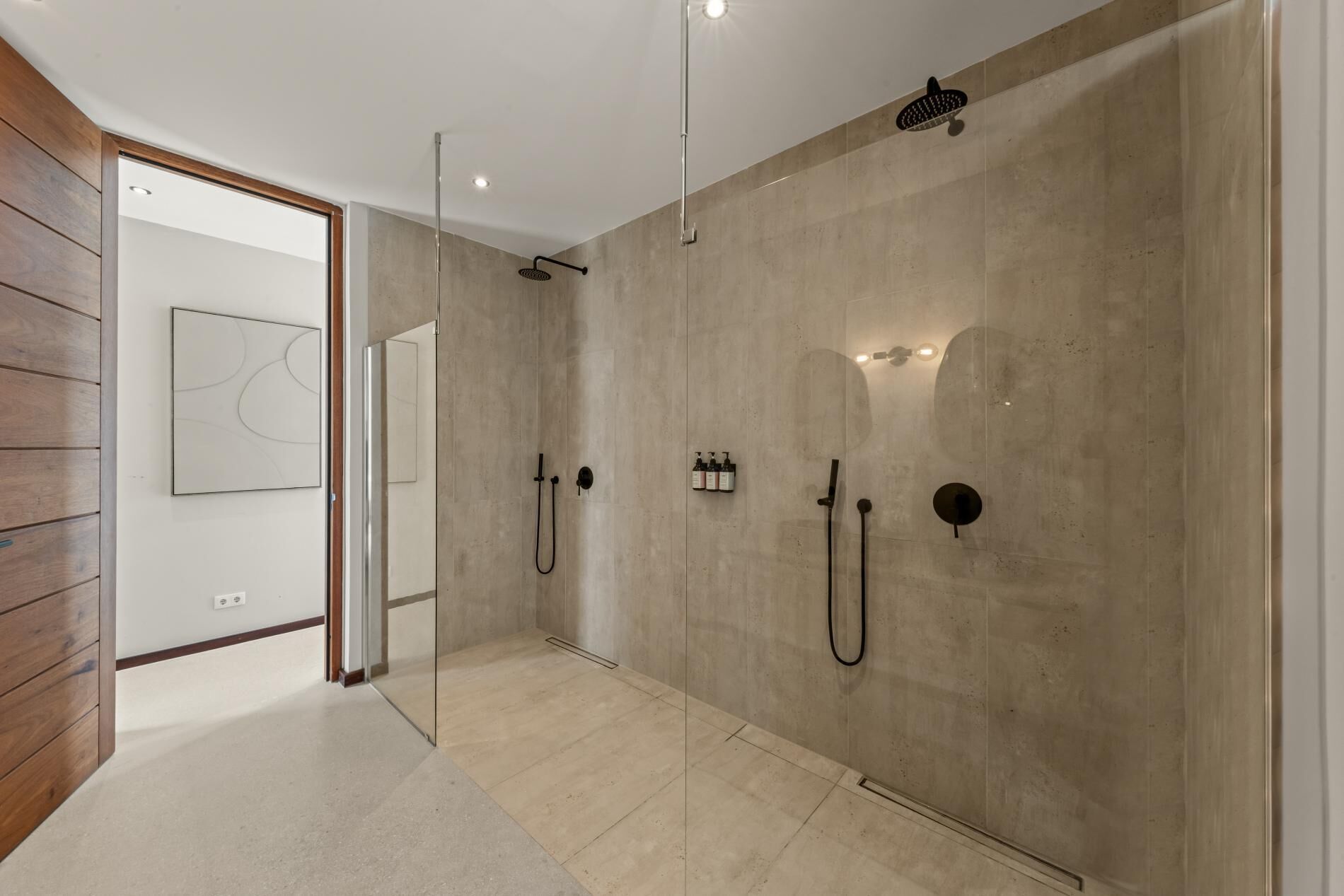 Een moderne badkamer met een grote spiegel, een douche met handdouche en een wandmengkraan.