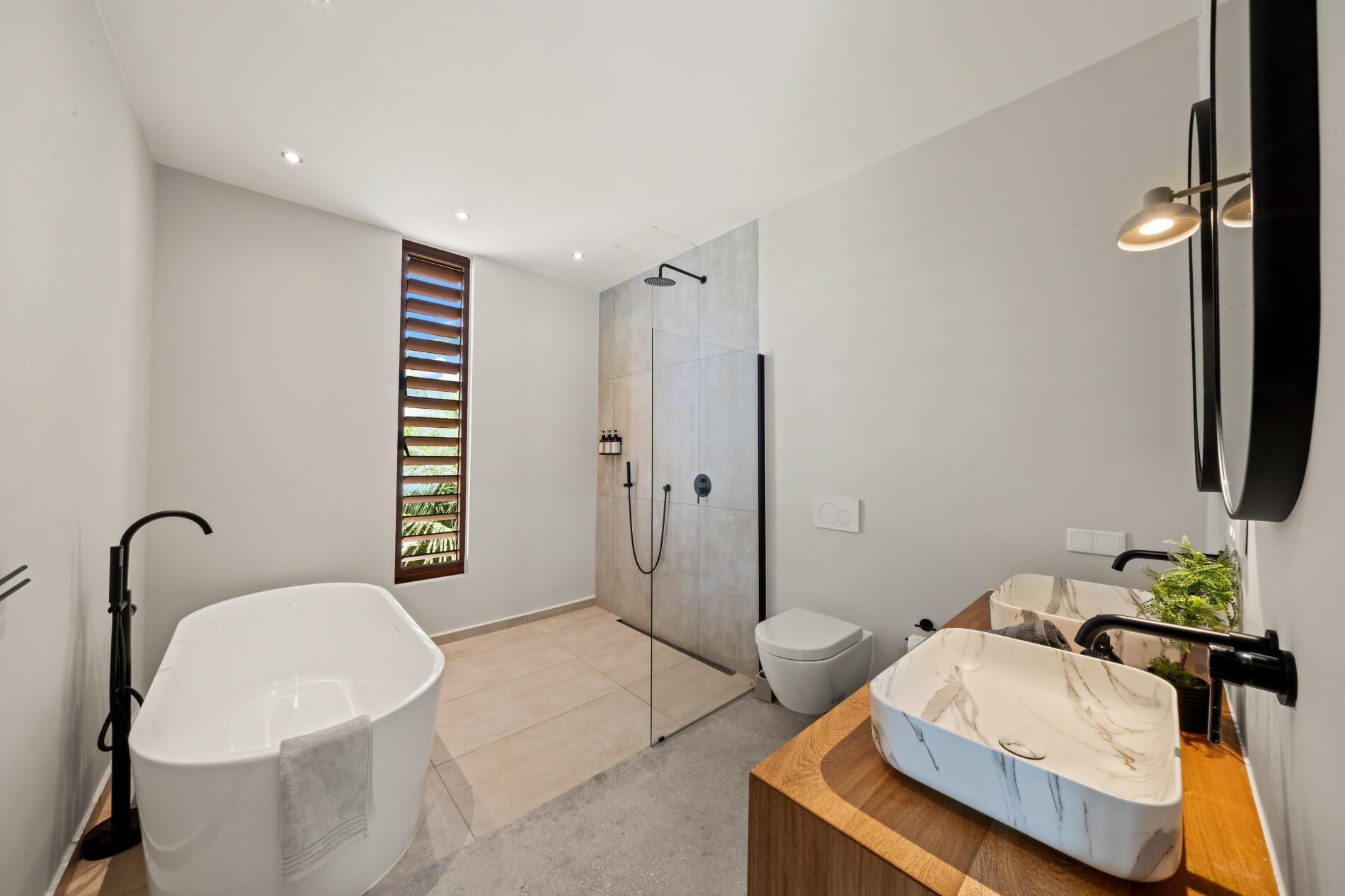 Un baño moderno con una bañera independiente, un box de ducha y un tocador con lavamanos de mármol.