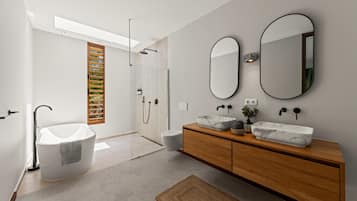 A modern bathroom with a freestanding bathtub, a wooden vanity with marble sinks, and a large mirror.