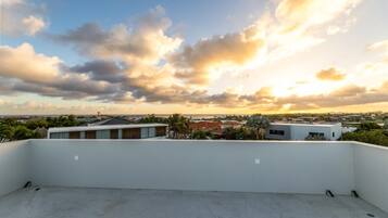 A rooftop with a view of a coastal town during sunset.