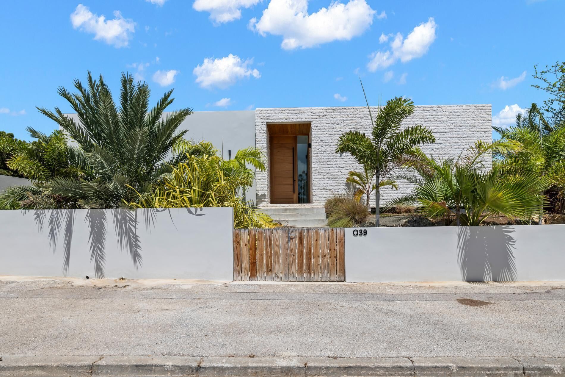Une maison moderne avec une façade blanche, une porte en bois et une petite fenêtre.