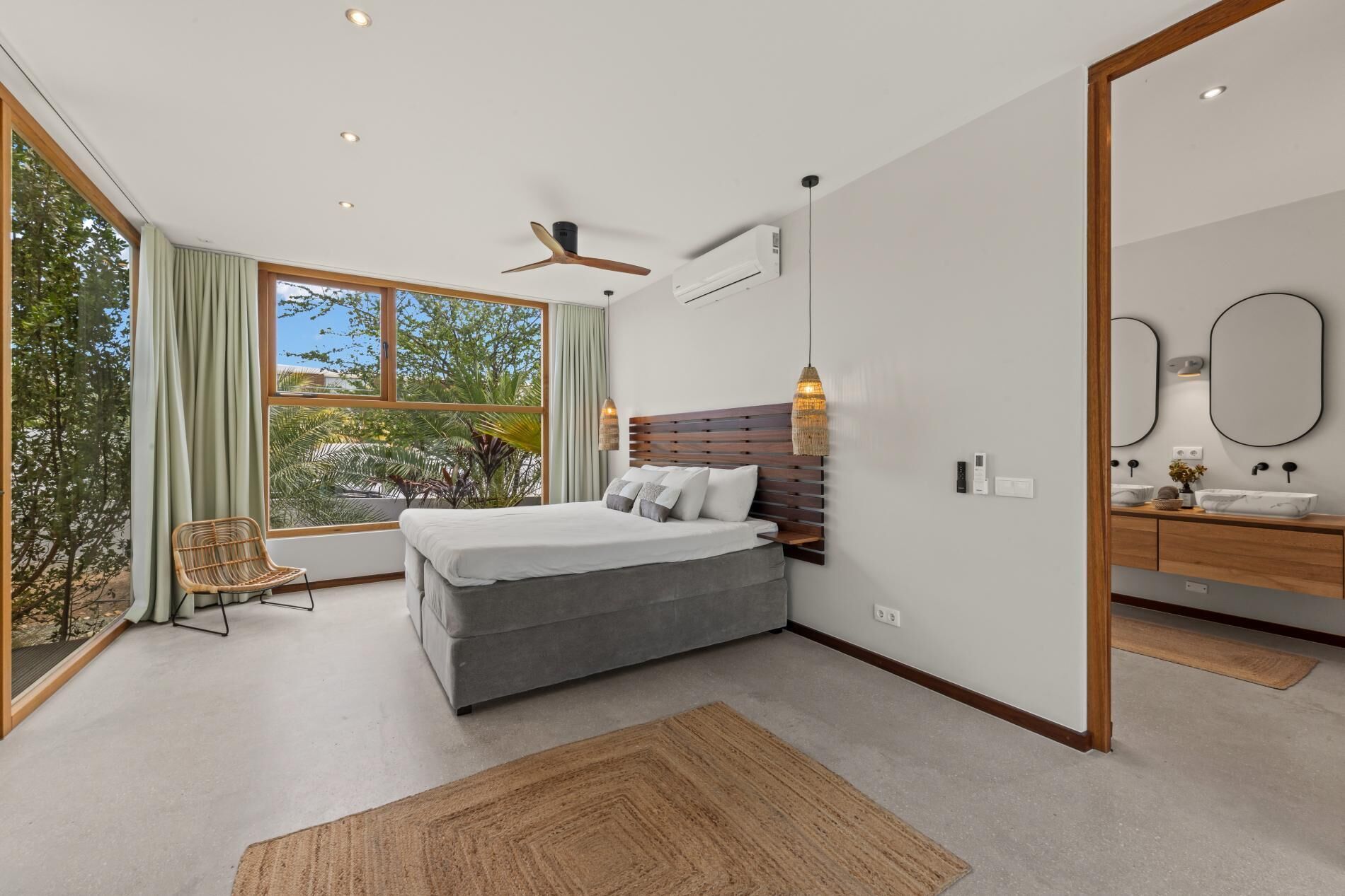 Un dormitorio moderno con una cama grande, un ventilador de techo y vistas por la ventana.
