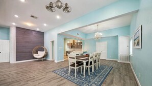 A spacious dining area with a wooden table, chairs, and a blue rug. - 1876 Historic Home • 2 Kitchens • Sleeps 10 • Cruise-Ready • (Galveston)
