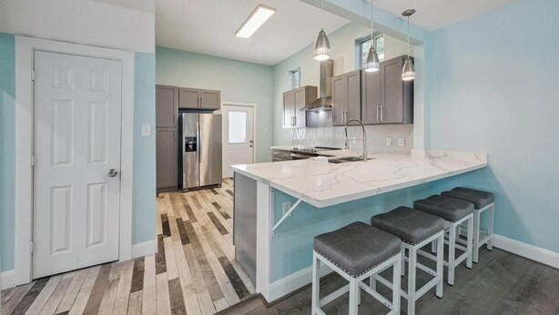 A modern kitchen with a large island, bar stools, and pendant lighting. - 1876 Historic Home • 2 Kitchens • Sleeps 10 • Cruise-Ready • (Galveston)