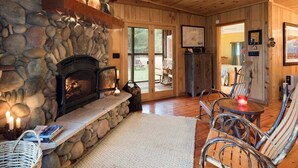 A cozy interior with a stone fireplace, wicker furniture, and a wooden ceiling.
