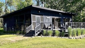 A single-story building with a covered porch, a staircase leading to the entrance, and a fenced outdoor area.