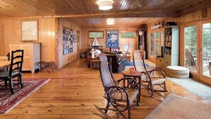 A wooden interior with a dining area, bookshelves, and a fireplace.