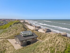 Um edifício moderno com teto de vidro que dá para uma praia com ondas.
