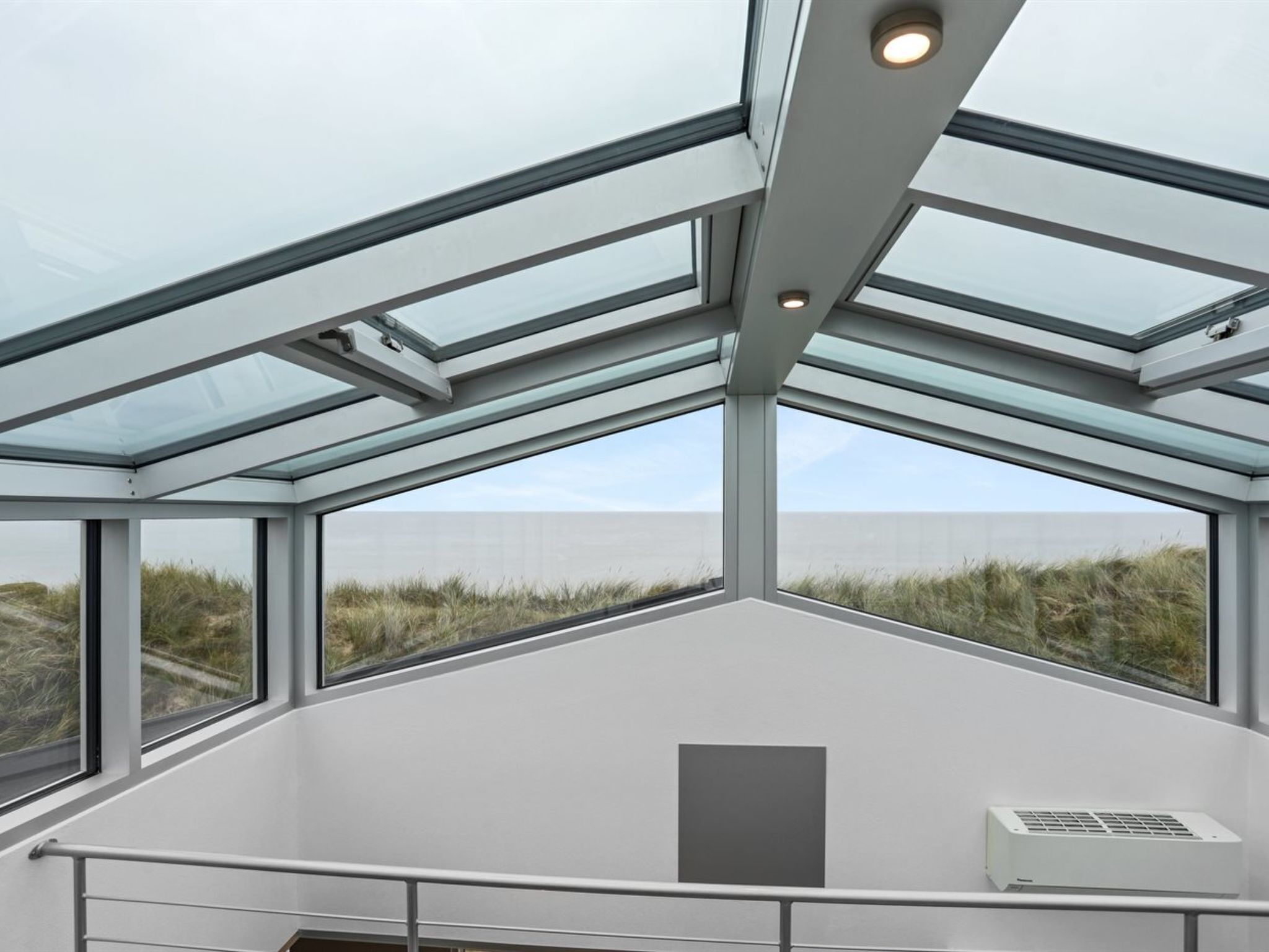 Un intérieur moderne avec un toit en verre, de grandes fenêtres et un appareil de climatisation.
