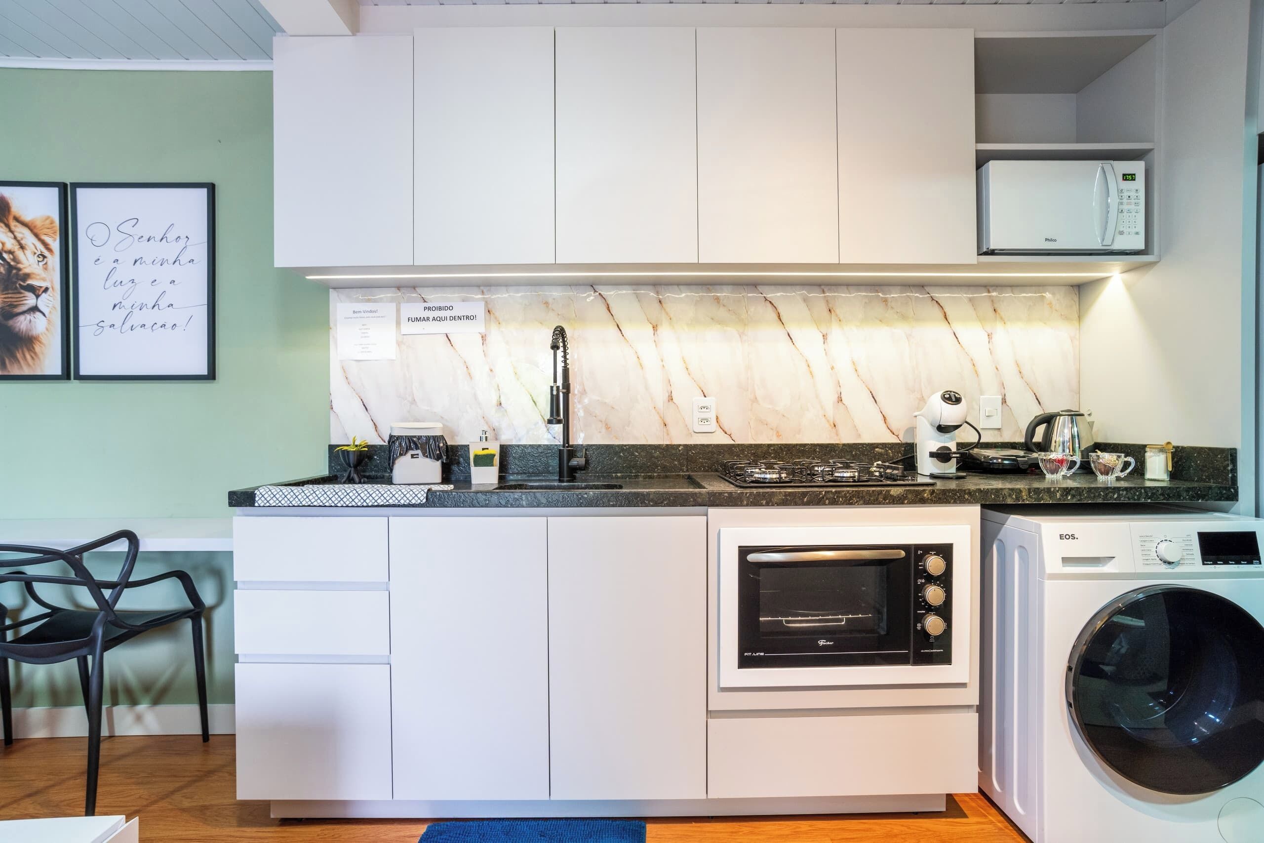 A compact kitchen with white cabinets, a built-in microwave, a stove, an oven, and a washing machine.