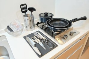 A kitchen counter with a frying pan, spatula, strainer, measuring cup, and kitchen utensils. - Sees Kinshicho II (Tokyo)