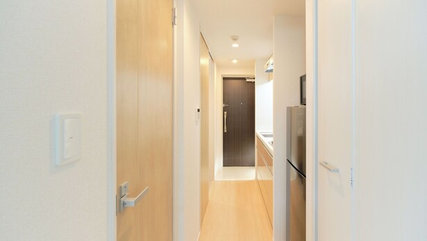 A hallway leading to a kitchen with a refrigerator, wooden flooring, and a door at the end. - Sees Kinshicho II (Tokyo)