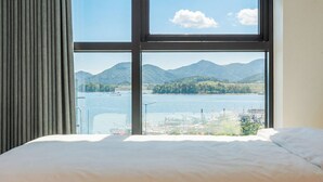 Una cama con vistas a un lago y montañas a través de una ventana.