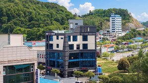 Un hotel de varios pisos con diseño moderno, ubicado en una zona verde y montañosa.