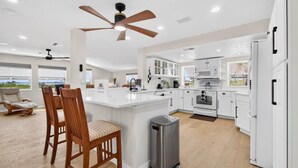 A modern kitchen with white cabinetry, a central island, a ceiling fan, and a view of the outdoors. - Spacious Waterfront Home_Sleeps 16_7BR_Spacious (Palmetto)