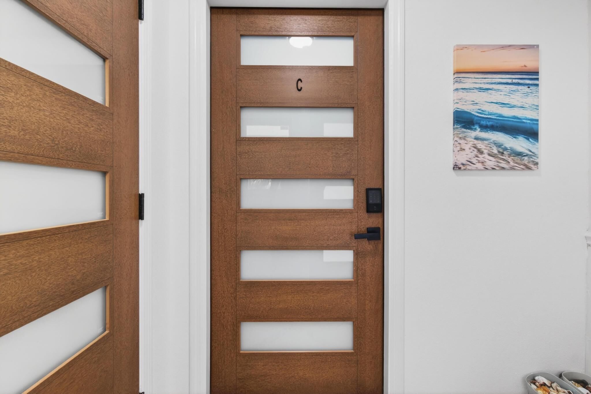 Una porta in legno con un pannello di vetro satinato, una maniglia nera e la lettera 'C' sopra la porta.
